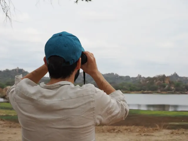 Phillip Wenzel from behind, binoculars raised, facing a wide landscape